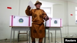 A man wearing traditional Mongolian clothes casts his vote at a polling station during Mongolia's presidential elections in Ulan Bator June 26, 2013. REUTERS/Mareike Guensche (MONGOLIA - Tags: POLITICS) - RTX1111K