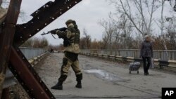 FILE - A Russia-backed rebel stands guard on a bridge which connects rebel-controlled territory and government-controlled territory in Stanytsia Luhanska, eastern Ukraine, Oct. 27, 2015.