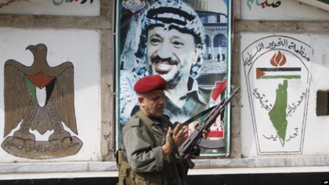 PLO security officer in front of a portrait of the late Palestinian leader at camp Ein el-Hilweh, Sidon, Lebanon, June 19, 2012.