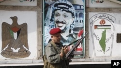 PLO security officer in front of a portrait of the late Palestinian leader at camp Ein el-Hilweh, Sidon, Lebanon, June 19, 2012.