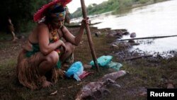 An Indigenous woman from the Pataxo Ha-ha-hae tribe looks at dead fish near Paraopeba river, after a tailings dam owned by Brazilian mining company Vale SA collapsed, in Sao Joaquim de Bicas near Brumadinho, Brazil, Jan. 28, 2019. 