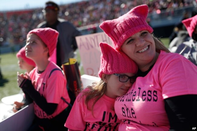 Eight-year-old Zoe Rodis leans on her mother Jennifer Rodis, right, during a Women's March rally, Jan. 21, 2018, in Las Vegas.