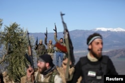 Turkish-backed Free Syrian Army fighters react as they hold their weapons near the city of Afrin, Syria, Feb. 19, 2018.