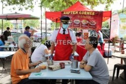 Mantan pilot Malaysia Azrin Mohamad Zawawi berbicara kepada pelanggan di warung makannya di Subang Jaya, Malaysia 7 November 2020. (Foto: REUTERS/Lim Huey Teng)