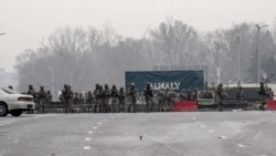 Servicemen block a street in central Almaty, Jan. 7, 2022, after violence that erupted following protests over hikes in fuel prices.