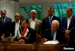 FILE PHOTO - Head of Hamas delegation Saleh Arouri and Fatah leader Azzam Ahmad sign a reconciliation deal in Cairo, Egypt, Oct. 12, 2017.