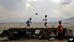 Afghan boys play with a ball on top of the remains of a Russian armored vehicle in Kabul, Afghanistan, October 6, 2011.