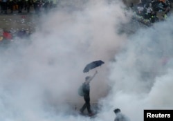 A protester walks in tear gas fired by riot policemen in Hong Kong's financial Central district outside the government headquarters on September 28, 2014.