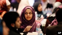 A young woman waves an American flag along with others at the beginning of a Muslim conference against terror and hate at the Curtis Culwell Center, Jan. 17, 2015, in Garland, Texas.