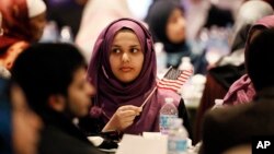 A young woman waves an American flag along with others at the beginning of a Muslim conference against terror and hate at the Curtis Culwell Center, Jan. 17, 2015, in Garland, Texas.