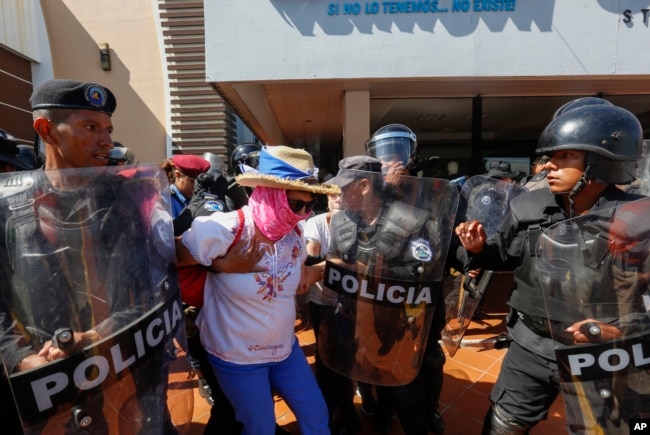 FILE - A masked anti-government protester is arrested by police as security forces disrupt an opposition march, coined "United for Freedom," in Managua, Oct. 14, 2018.
