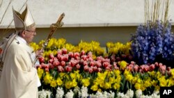Paus Francis berjalan melewati bunga saat merayakan Misa Paskah, di Lapangan Santo Petrus, di Vatikan, 16 April 2017.
