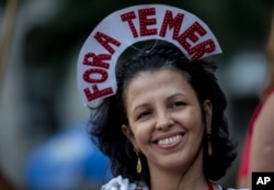 A reveler wears a crown that reads in Portuguese: "Out Temer" during a carnival street party in Rio de Janeiro, Feb. 24, 2017. Merrymakers took to the streets to protest Brazil's President Michel Temer.