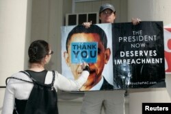 FILE - A health care reform supporter, left, blocks a sign held by a Lyndon LaRouche supporter at a rally in Hollywood, California, Aug. 11, 2009.