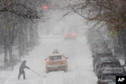 A man shovels snow as traffic makes its way east on 81st street, Jan. 4, 2018, on the Upper East Side of Manhattan.