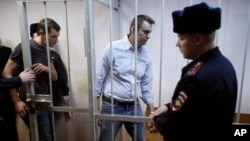 Russian opposition activist and anti-corruption crusader Alexei Navalny, 38, second right, and his brother Oleg Navalny, left, enter into the cage at a court in Moscow, Dec. 30, 2014.