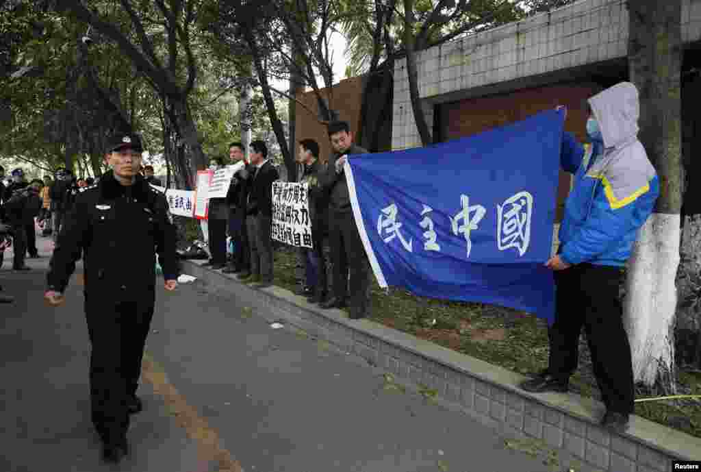 A police officer walks past supporters of Southern Weekly demonstrating outside the office of the liberal newspaper in the southern Chinese city of Guangzhou, January 9, 2013.