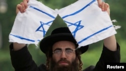 Seorang umat Yahudi Ortodoks anti-Zionis menyobek bendera Israel dalam protes melawan negara Israel di New York.