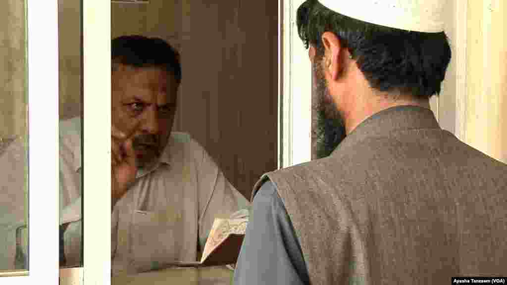 طورخم سرحد پر پاکستانی امیگریشن کا اہلکار ایک افغان شخص کے پاسپورٹ کی جانچ کر رہا ہے