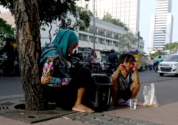 Seorang anak bersama neneknya beristirahat di jalur pejalan kaki di Jakarta, 10 Oktober 2019. Maraknya makanan murah dan mengenyangkan, tapi minim gizi mengakibatkan jutaan anak mengalami masalah kesehatan. (Foto: AFP)