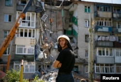 A rescuer stands near a shattered five-storey building, which was damaged by a recent shelling, in the eastern Ukrainian town of Slaviansk July 16, 2014.