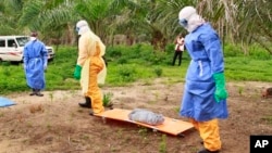 The wrapped remains of a new born child suspected of contracting the Ebola virus, lays on a stretcher as health workers, dressed in Ebola protective gear, move the body for burial in Dubreka, Guinea, Jan. 19, 2017. 