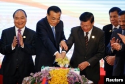 FILE - From left, Vietnamese President Tran Dai Quang, Chinese Premier Li Keqiang, Laos Prime Minister Thongloun Sisoulith, Philippines President Rodrigo Duterte, and Brunei's Sultan Hassanal Bolkiah cut a cake during the ASEAN-China Summit in Vientiane, Laos, Sept. 7, 2016.