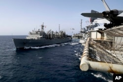 In this Sunday, May 19, 2019, photo released by the U.S. Navy, the fast combat support ship USNS Arctic transports cargo to the Nimitz-class aircraft carrier USS Abraham Lincoln during a replenishment-at-sea in the Arabian Sea.