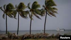 FILE - Boats are seen as palms are moved by the wind in Cap-Haitien, Haiti, Sept. 7, 2017. A boat with Haitian migrants sank off the Bahamas Saturday.