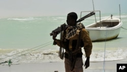 A Somali, part armed militia, part pirate, carries his high-caliber weapon on a beach in the central Somali town of Hobyo on Aug. 20, 2010.