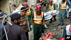 Pakistani police officers visit the site of explosion as rescue workers remove a dead body after a bomb blast in the shrine of Sufi Farid Shakar Ganj in Pak Pattan, west from Lahore, 25 Oct. 2010