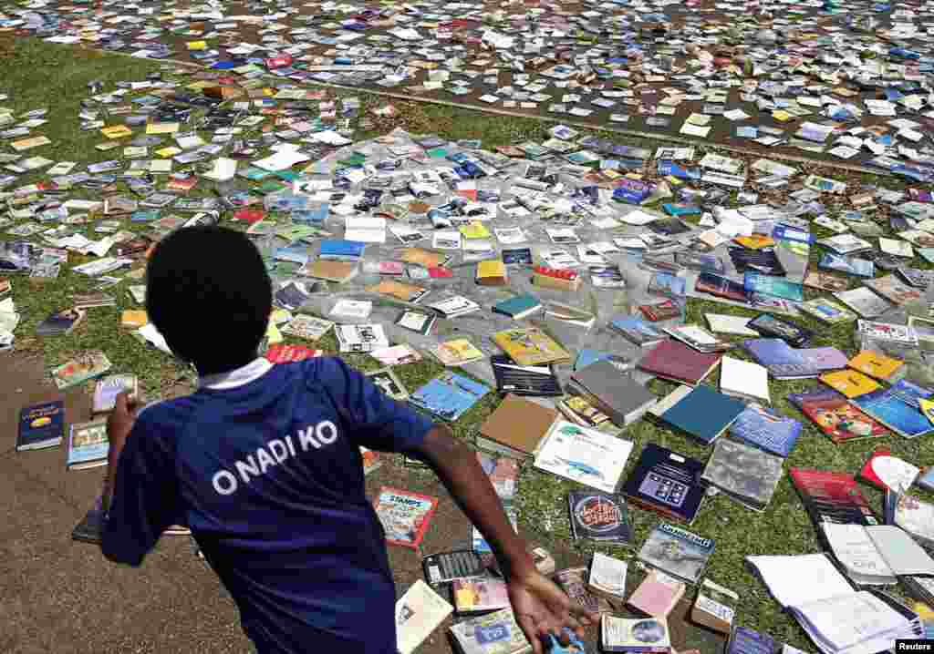 Seorang anak laki-laki berlari melewati buku-buku yang sedang dijemur setelah atap perpustakaan sekolah dibawa terbang Siklon Pam di Port Vila, ibukota Vanuatu&nbsp;​(18/3). ​(AFP/Jeremy Piper)