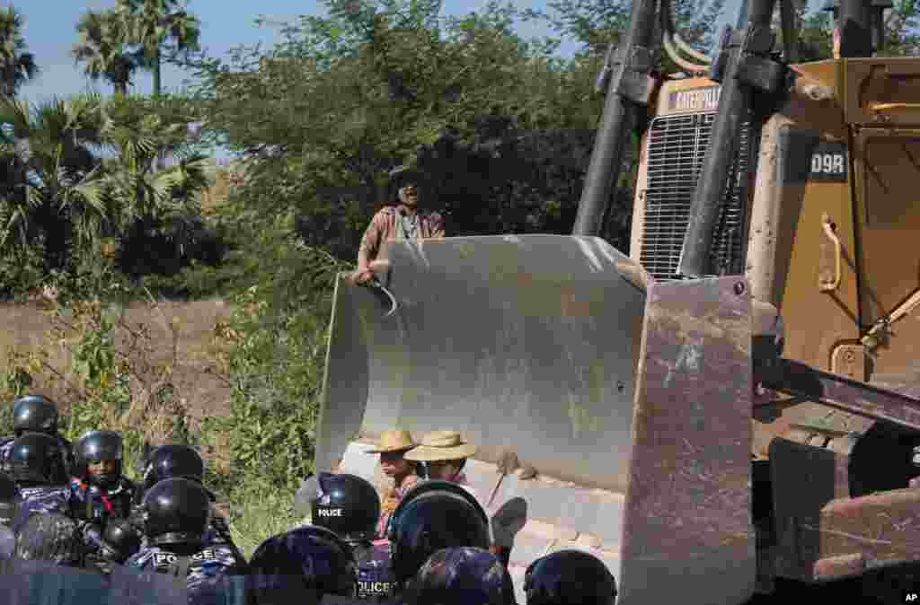 Farmers confront a bulldozer, owned by the Chines mining company, from moving forward as riot police gather at Letpadaung copper mine, Monywa in northwestern Myanmar, Dec. 22, 2014.