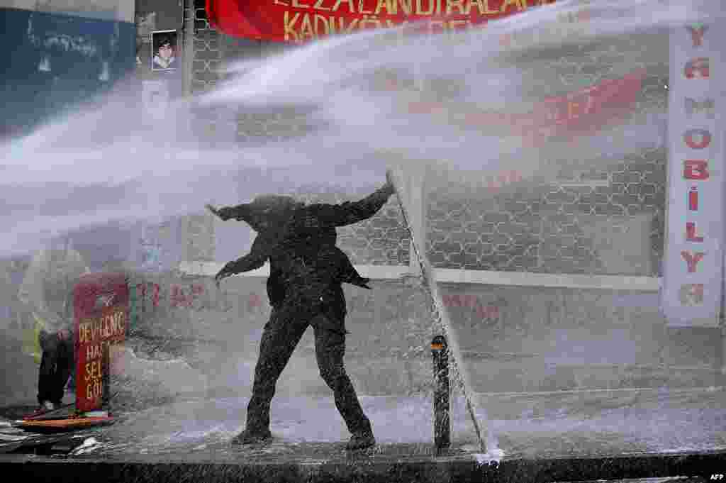 Homem se defende de jato d&#39;água da polícia com placa, em protestos em Istanbul em memória de um adolescente que morreu em 2013 durante uma manifestação contra o governo. A morte do jovem tornou-se um símbolo para a oposição ao presidente turco.