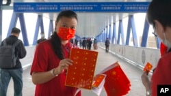 一名支持北京政府的女子在香港人行道上發放中國國旗。（2021年4月15日）
