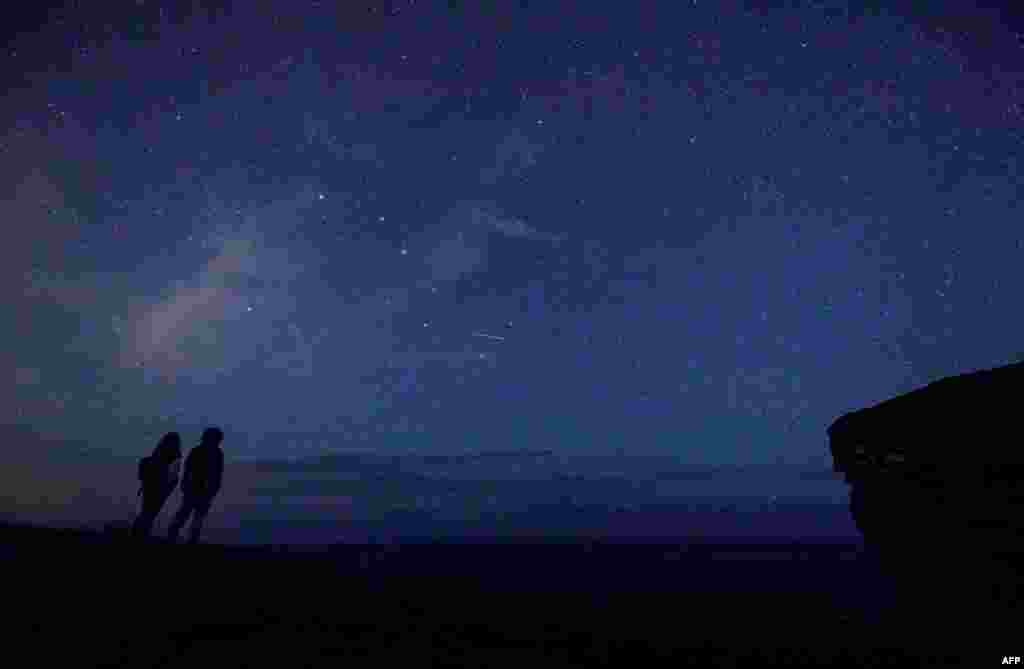 A couple enjoy Perseid meteor along the Milky Way illuminating the dark sky near Comillas, Cantabria community, northern Spain, during the &quot;Perseids&quot; meteor shower, Aug. 12, 2017.