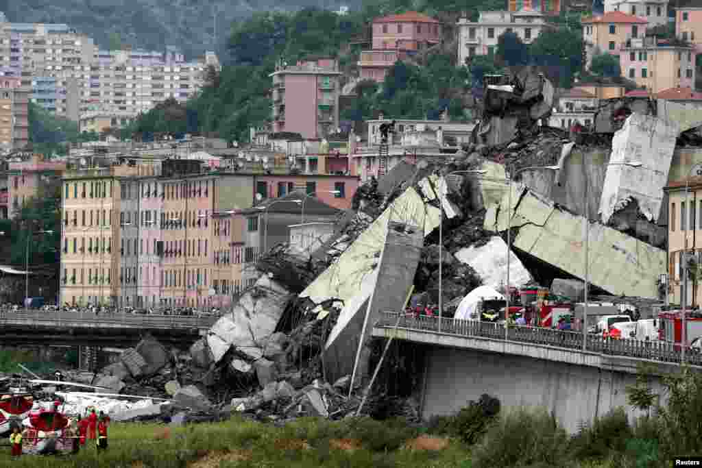 The collapsed Morandi Bridge is seen in the Italian port city of Genoa, Italy. A 50-meter-high section of the bridge, including a tower that anchored several supports, crashed down with as many as 35 vehicles, onto the roofs of warehouses and other buildings, plunging huge slabs of reinforced concrete into a riverbed. Up tp 35 were killed, Italy’s ANSA news agency said, citing fire brigade sources, while the official body count remained at about 20.