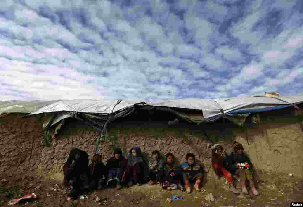 Internally displaced Afghan children sit near their shelter at a refugee camp in Kabul, Afghanistan, January 19, 2013. 