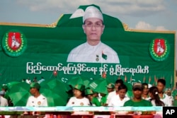 Members of the military-backed Union Solidarity and Development Party (USDP) stand in front of a portrait of Myanmar President Thein Sein on display during a campaign rally for the upcoming general election, Nov 6, 2015, in outskirts of Yangon.