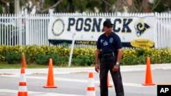 Un guardia de seguridad se encuentra frente a la entrada del Centro Comunitario Judío David Posnack y de la Escuela Judaica David Posnack después de que la gente fue evacuada debido a una amenaza de bomba, el lunes 27 de febrero de 2017 en Davie.