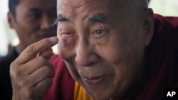 Tibetan spiritual leader the Dalai Lama points to his swollen right eye as he talks to journalists before boarding his chartered flight in Dharmsala, India, Jan. 19, 2016. 