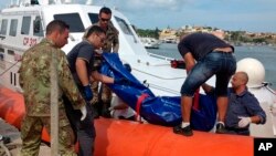 The body of a drowned migrant is being unloaded from a Coast Guard boat in the port of Lampedusa, Italy, Oct. 3, 2013. 