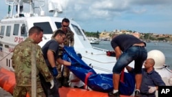 Para penjaga pantai mengangkat jenazah migran yang menjadi korban kapal terbalik di pelabuhan Pulau Lampedusa, Italia (3/10). 