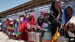 FILE - Displaced Somali girls who fled the drought in southern Somalia stand in a queue to receive food handouts at a feeding center in a camp in Mogadishu, Somalia, Feb. 25, 2017.