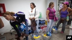 FILE - Shoppers wait in line to check out at a supermarket in the Propatria neighborhood of Caracas, Venezuela.