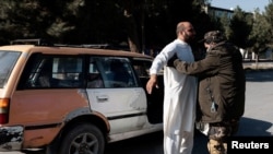 စစ်ဆေးရေးဂိတ်တခုမှာ တာလီဘန်တိုက်ခိုက်ရေးသမားတယောက်က ခရီးသည်တဦးကို စစ်ဆေးရှာဖွေနေစဉ်။ (နိုဝင်ဘာ ၅၊ ၂၀၂၁)