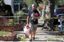 A man carries supplies as he walks over fallen tree limbs and downed power lines in the aftermath of Tropical Storm Isaias in the Sheepshead Bay Area of Brooklyn, New York, Aug. 4, 2020.