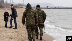 File - Local volunteers patrol the city beach in Mariupol, Donetsk region of Ukraine.