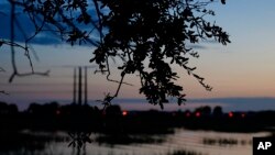 FILE - Cars drive by a main road on the mainland near Daufuskie Island, Wednesday, Sept. 13, 2023, in S.C. Long dirt roads were once occupied by a bustling community that had its own bartering system and a lucrative oyster industry. 