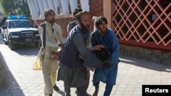 Afghan men carry a wounded person to the hospital after a suicide attack in Jalalabad, Afghanistan, June 13, 2019. 